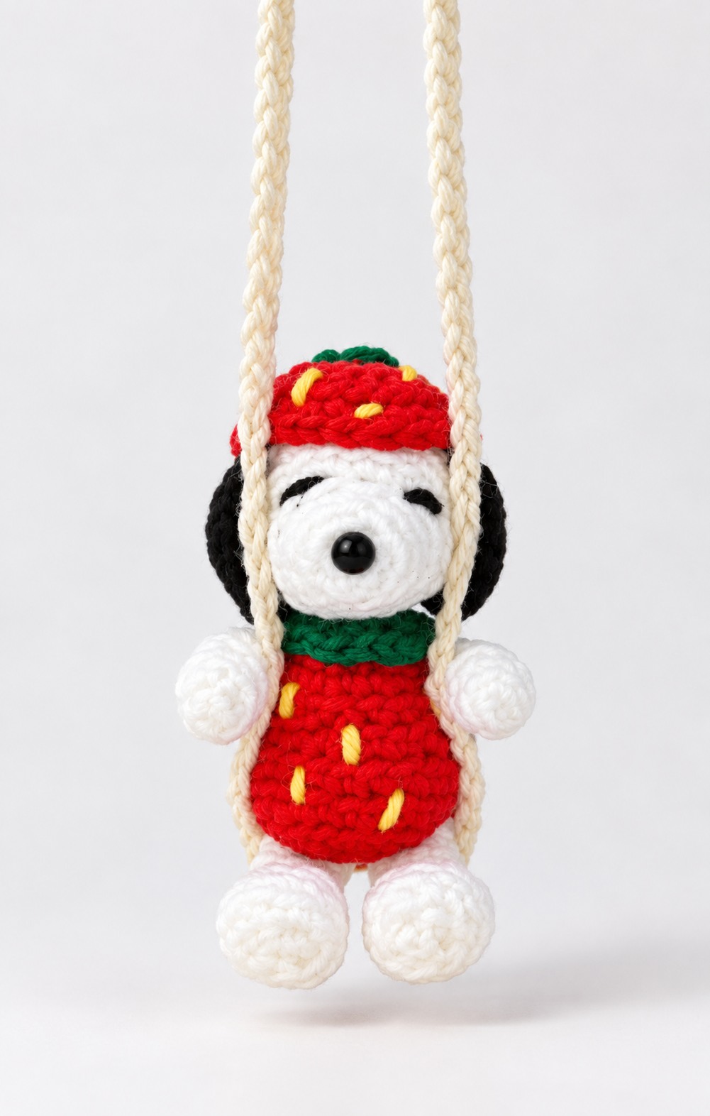 White crochet dog in a strawberry outfit on a swing