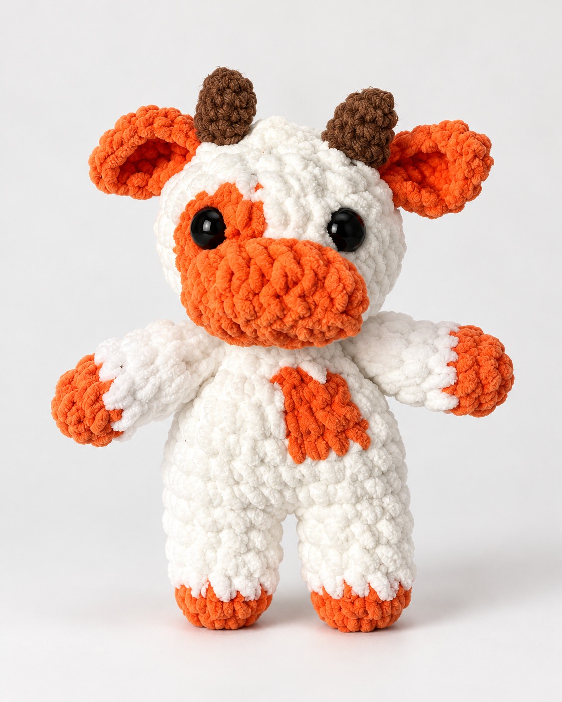 White and orange crochet cow plushie with brown horns