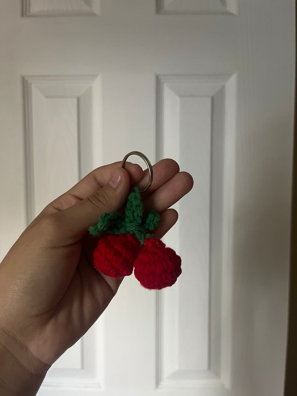 Two red crochet cherries with green stems on a keyring.