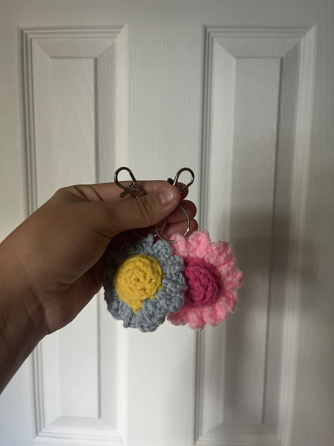 Gray and yellow daisy and pink daisy crochet keychains, sold individually.