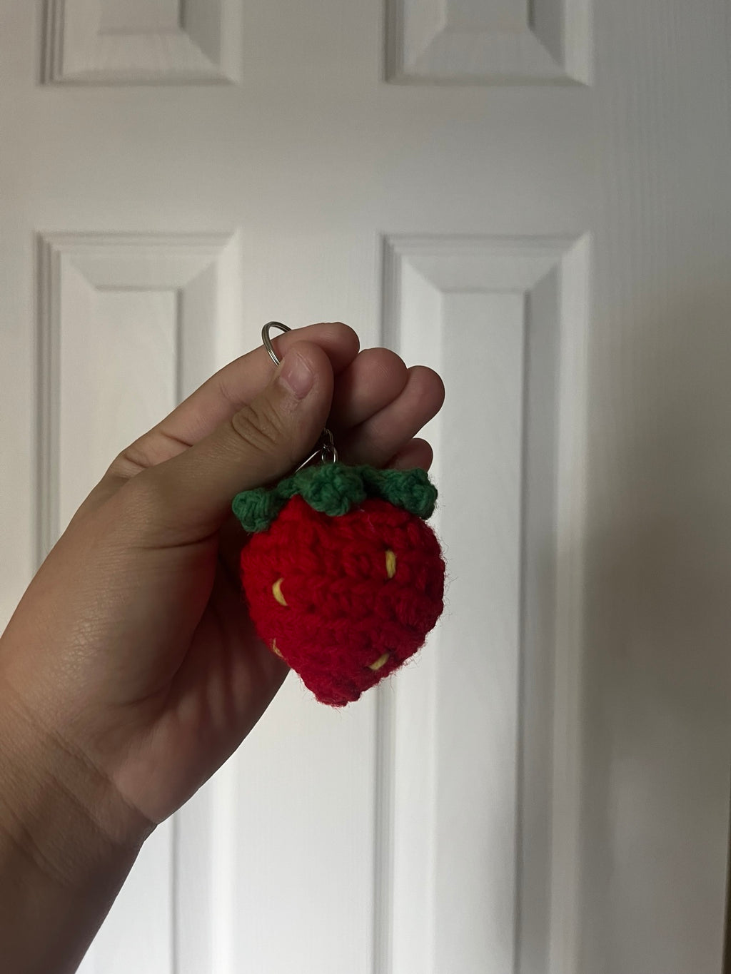 Red crochet strawberry with green leaves and yellow seeds.