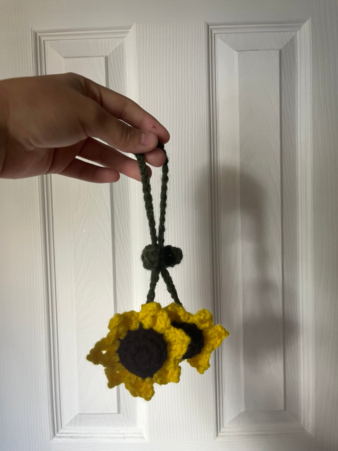 Two yellow crochet sunflowers with dark centers and a green loop.